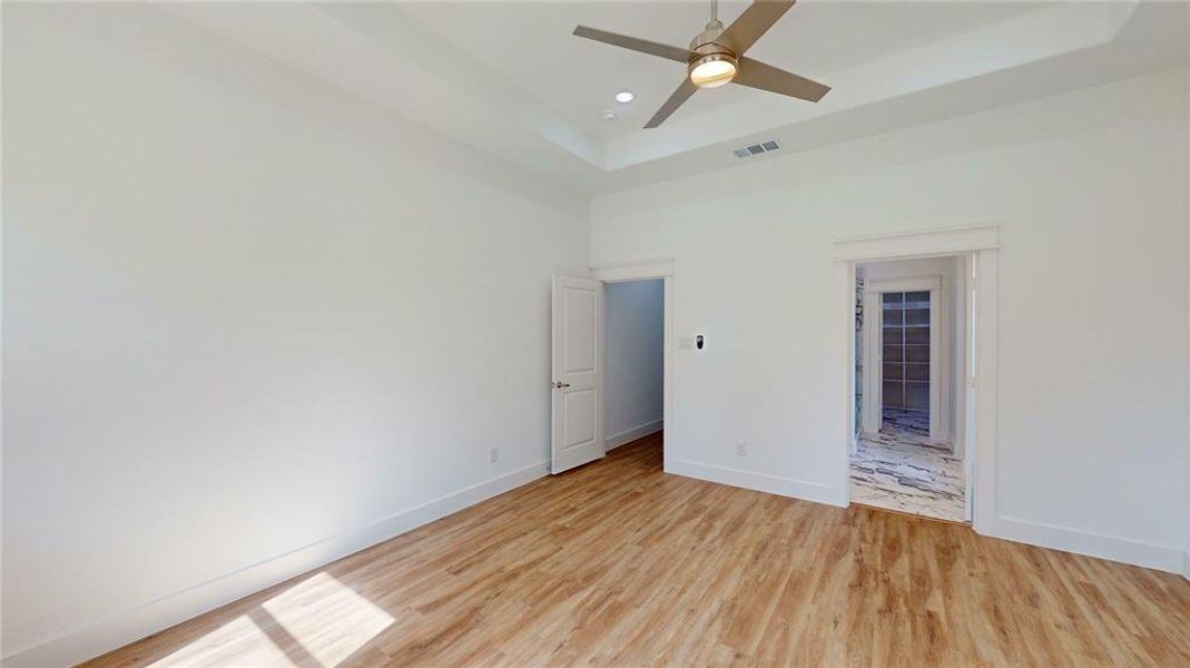 Unfurnished bedroom with baseboards, visible vents, and a tray ceiling