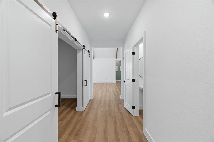 Hallway featuring wood-finish flooring, recessed lighting, and white walls Hallway featuring wood-finish flooring, recessed lighting, and white walls