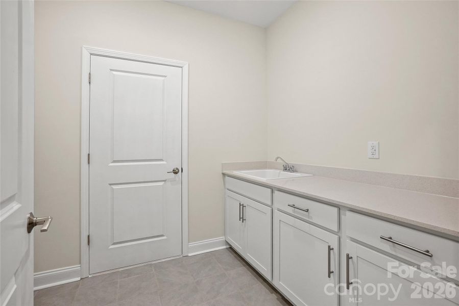 Large laundry room includes cabinets and sink