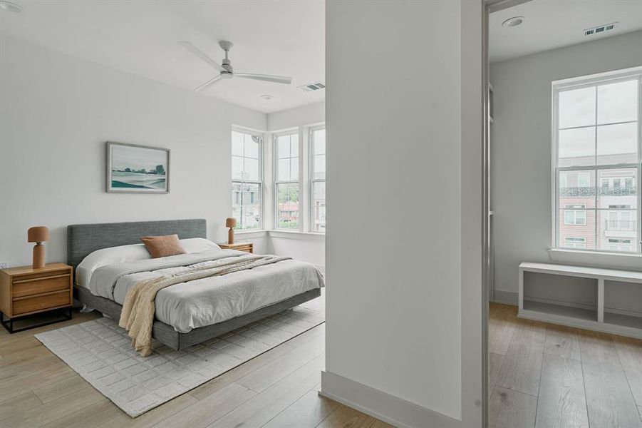 Spacious room featuring multiple large windows, light wood-finish flooring, and a ceiling fan Spacious room featuring multiple large windows, light wood-finish flooring, and a ceiling fan