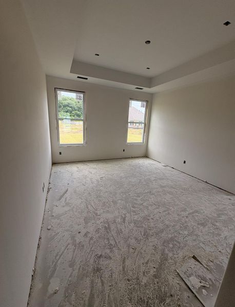 Spacious room featuring a tray ceiling with recessed lighting, two double-hung windows, and a neutral color palette Spacious room featuring a tray ceiling with recessed lighting, two double-hung windows, and a neutral color palette