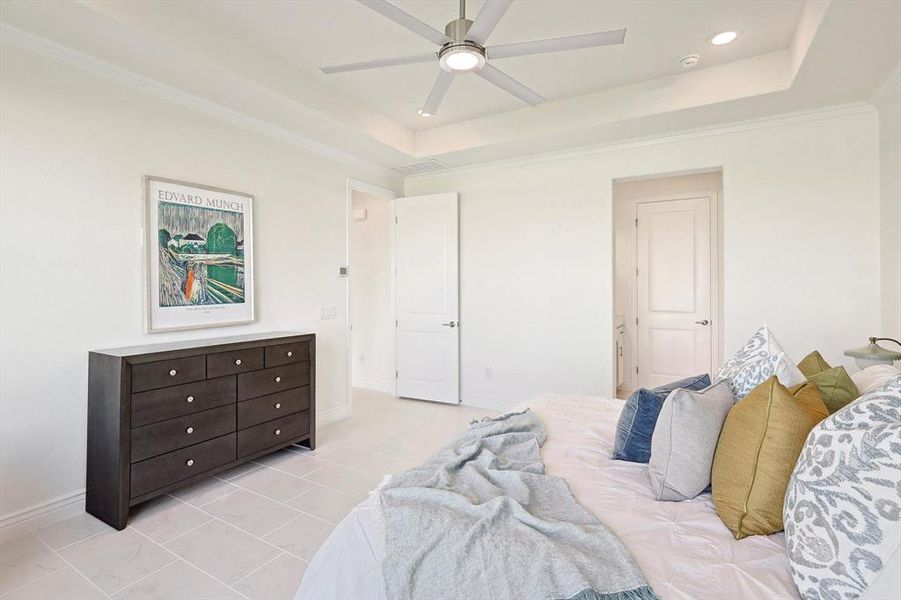 Tiled bedroom featuring ornamental molding, ceiling fan, and a raised ceiling