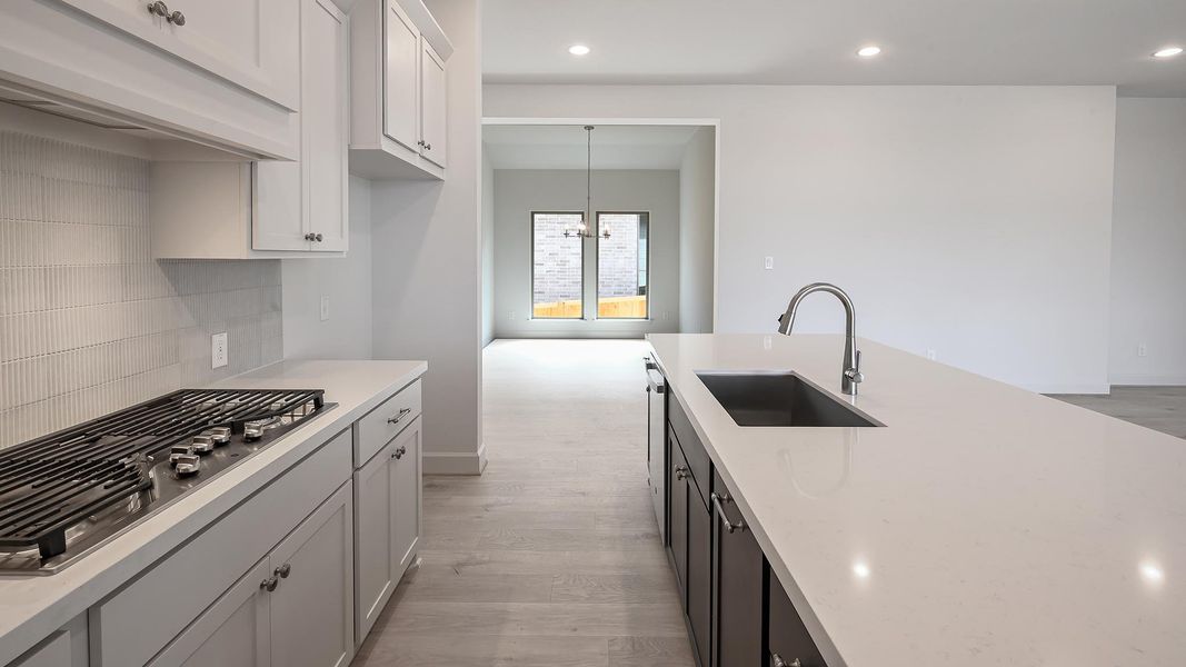 Kitchen featuring light wood finished floors, appliances with stainless steel finishes, recessed lighting, ventilation hood, and hanging light fixtures