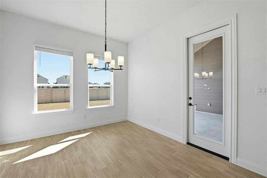 Bright interior space featuring wood-finish flooring, a contemporary chandelier, and two large windows