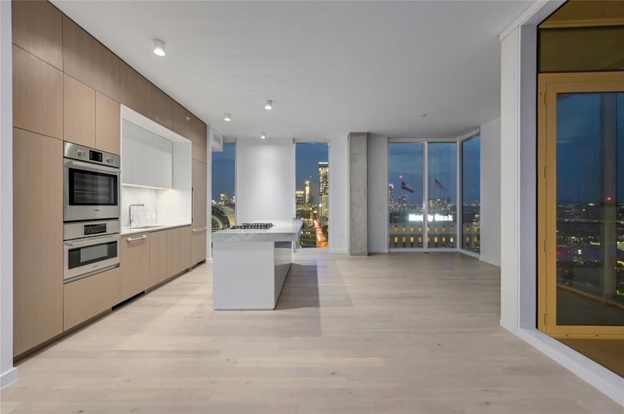 Kitchen with modern cabinets, light wood-style floors, light countertops, and open floor plan Kitchen with modern cabinets, light wood-style floors, light countertops, and open floor plan