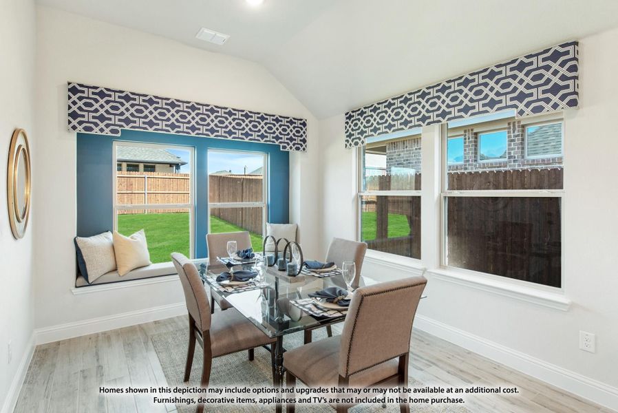 Dining area with glass table, four chairs, window seat, and vaulted ceiling with large windows overlooking backyard