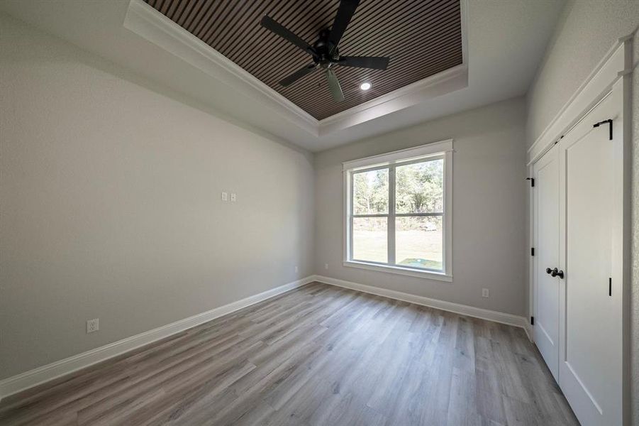 Unfurnished bedroom featuring a closet, a tray ceiling, light wood finished floors, and a ceiling fan Unfurnished bedroom featuring a closet, a tray ceiling, light wood finished floors, and a ceiling fan