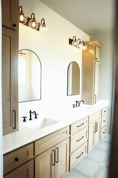 Double vanity with light wood-finish cabinetry and white countertops