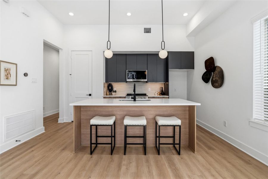 Duplex kitchen featuring a quartz island with seating, sleek cabinetry, and modern pendant lighting.