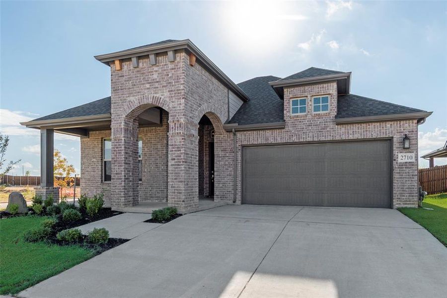 French country style house with brick siding, roof with shingles, concrete driveway, and an attached garage