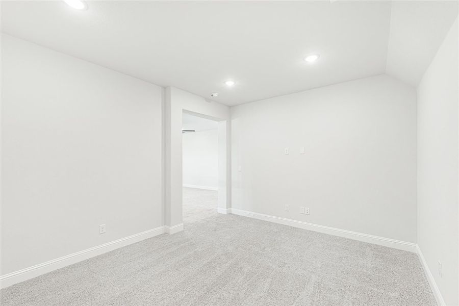 Empty room with light gray carpet, white walls, recessed lighting, and open doorway