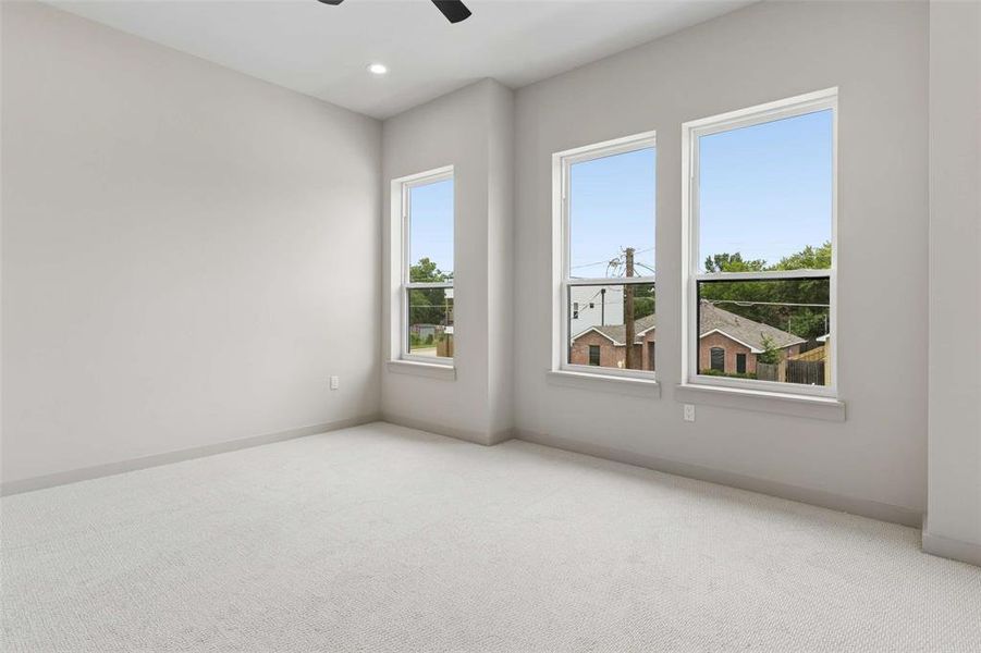 Bright interior space featuring three large windows, light gray walls, and plush carpeting. Bright interior space featuring three large windows, light gray walls, and plush carpeting.