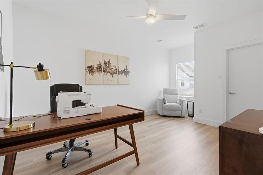 Bright interior room featuring wood-finish flooring, a contemporary ceiling fan, white baseboards, and a window with horizontal blinds