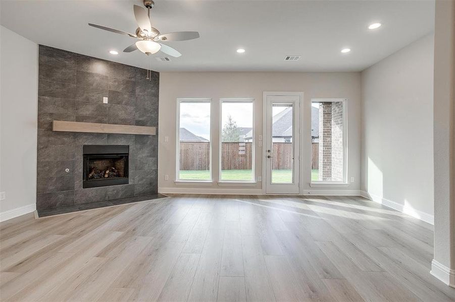 Unfurnished living room with a tile fireplace, light hardwood / wood-style flooring, and ceiling fan