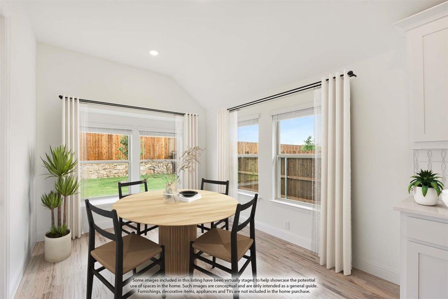 Bright dining area with round wood table, four chairs, vaulted ceiling, and large windows overlooking backyard Bright dining area with round wood table, four chairs, vaulted ceiling, and large windows overlooking backyard