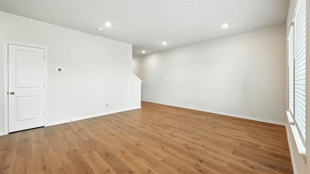 Spacious interior room featuring wood-finish flooring, recessed lighting, and a neutral color palette