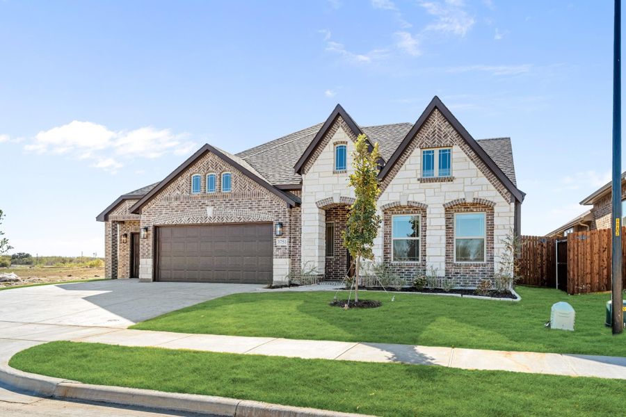 Two-story home with brick and stone exterior, two-car garage, and manicured front lawn Two-story home with brick and stone exterior, two-car garage, and manicured front lawn
