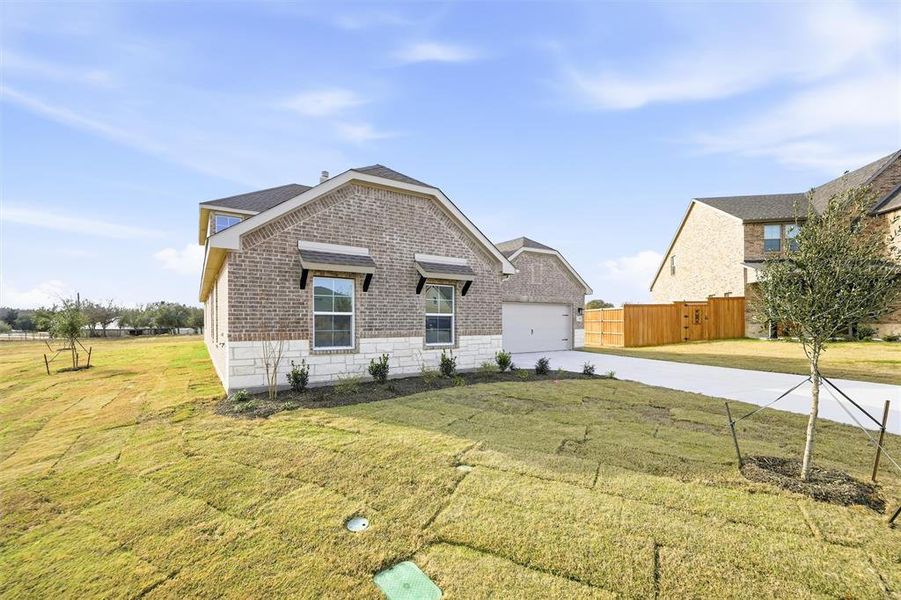 Rear view of property with concrete driveway, brick siding, and an attached garage