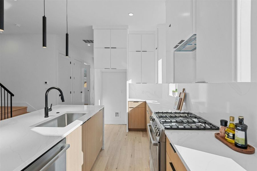 Kitchen with modern cabinets, light stone countertops, appliances with stainless steel finishes, white cabinets, and recessed lighting Kitchen with modern cabinets, light stone countertops, appliances with stainless steel finishes, white cabinets, and recessed lighting