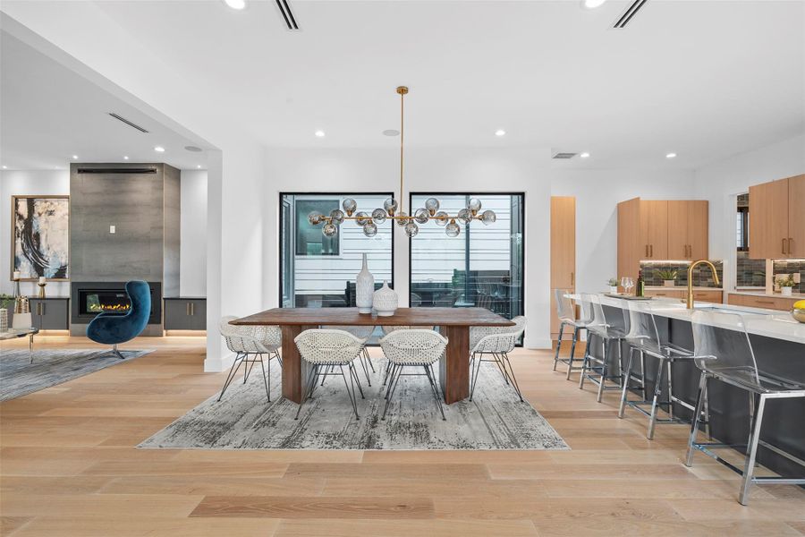 This open-concept living space features light wood flooring, a built-in fireplace, and a kitchen island with seating