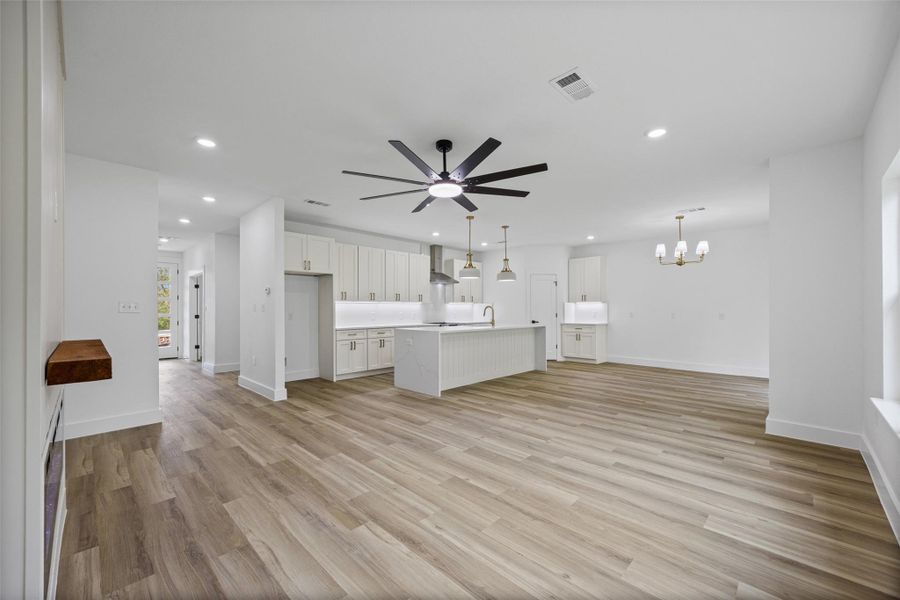 Open-concept living space featuring wood-finish flooring, recessed lighting, and a contemporary ceiling fan Open-concept living space featuring wood-finish flooring, recessed lighting, and a contemporary ceiling fan