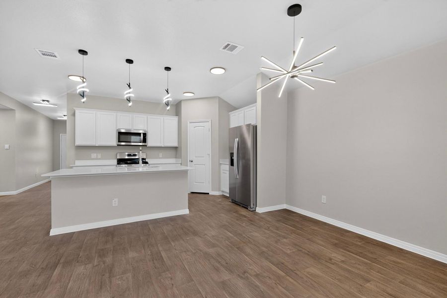 Rich wood flooring anchors this open layout connecting the dining space and kitchen.