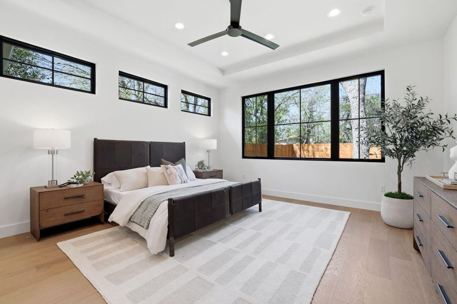 Bedroom featuring a raised ceiling, ceiling fan, recessed lighting, and light wood finished floors