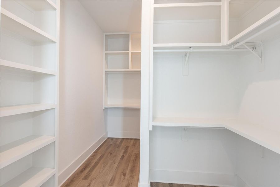 Spacious primary closet with custom built-ins for optimal organization. Spacious primary closet with custom built-ins for optimal organization.
