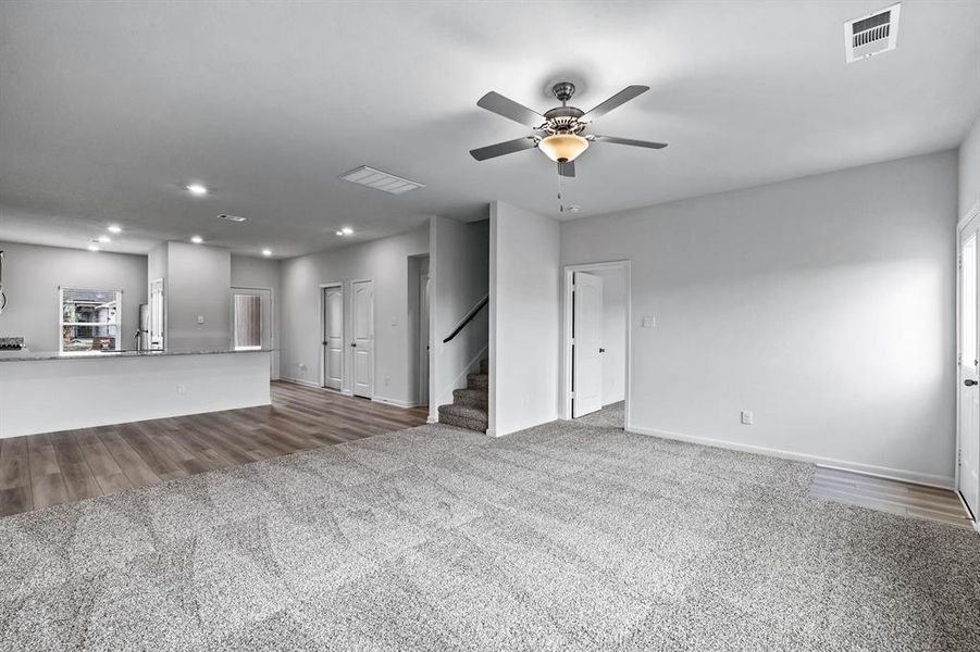 Unfurnished living room featuring light carpet and ceiling fan