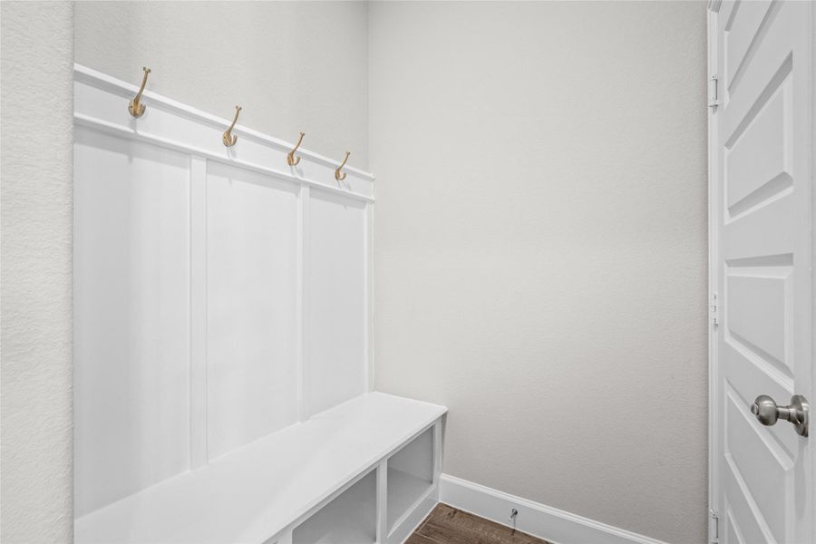 Essential utility: Built-in mud area/bench with coat hooks near the garage entry.