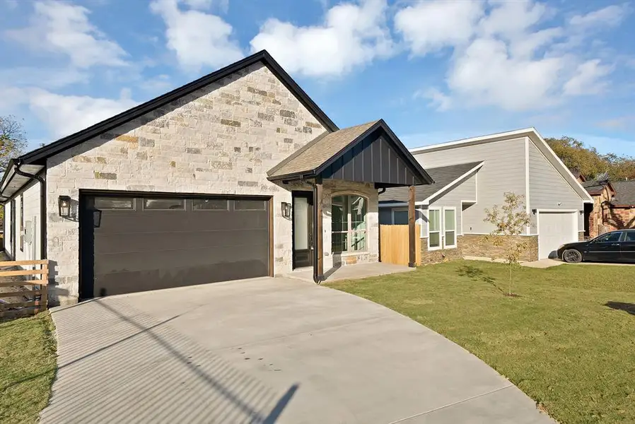 View of front of house featuring stone siding, a garage, driveway, and board and batten siding