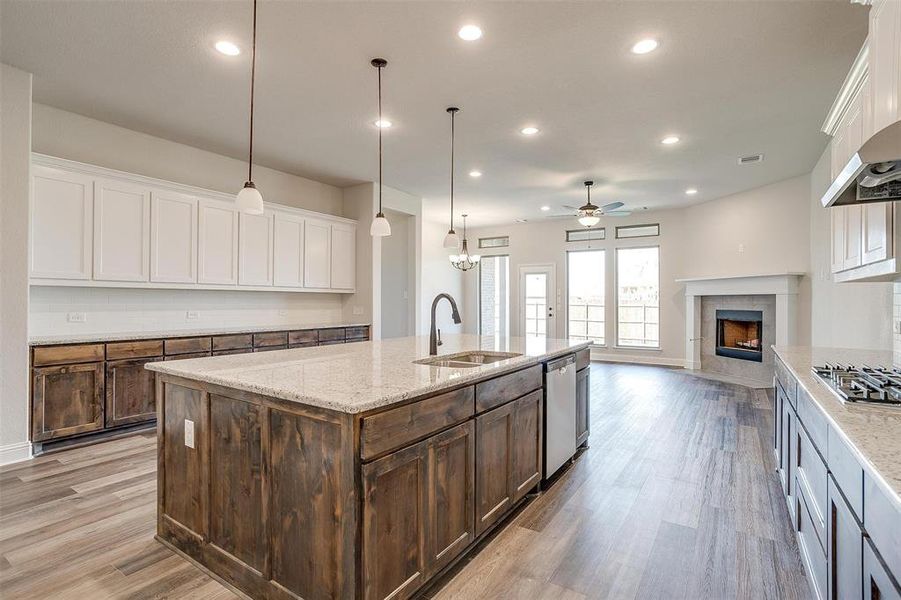 Kitchen with pendant lighting, ceiling fan, a fireplace, and sink