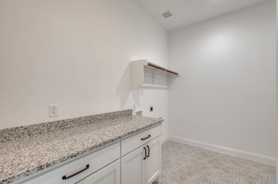 Clothes washing area with electric dryer hookup, cabinets, and washer hookup