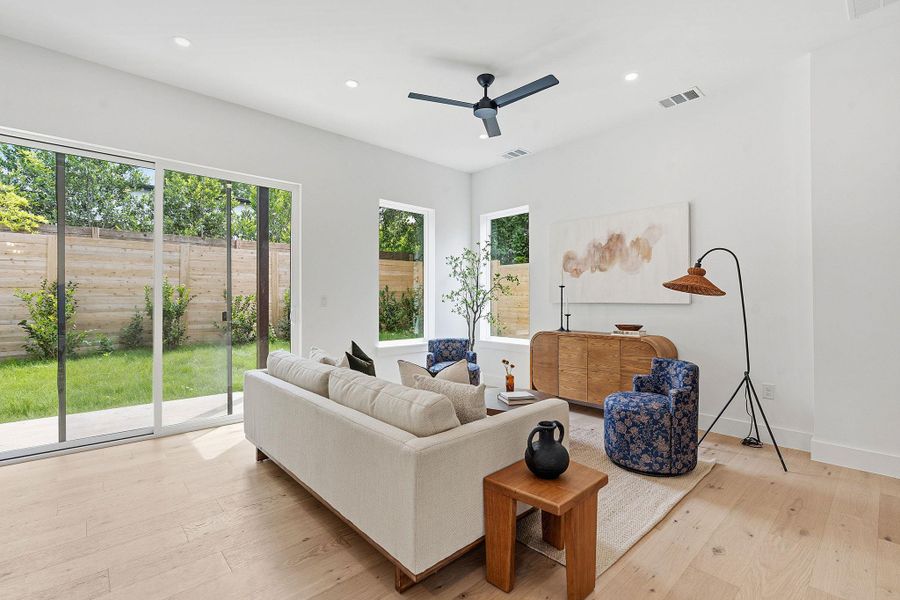 Bright living area featuring wood-finish flooring and a contemporary ceiling fan