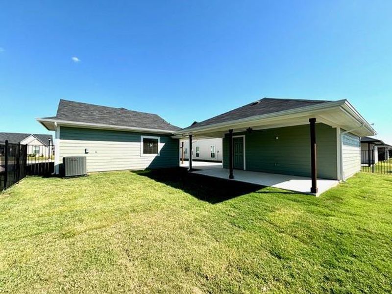 Rear view of property with a lawn, a patio, and central AC