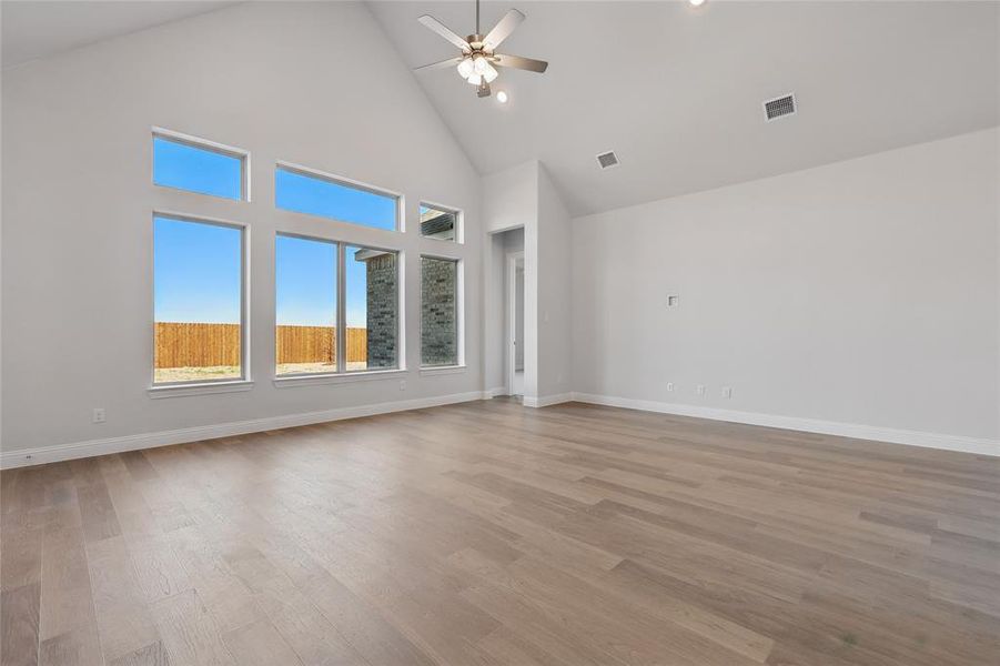 Spare room with a high ceiling, a ceiling fan, and light wood-style flooring
