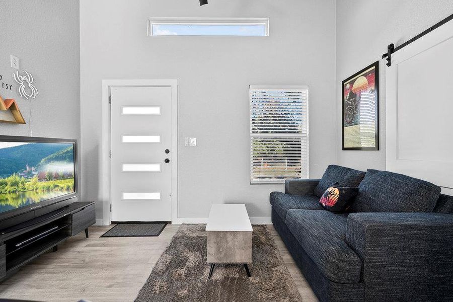 Living area featuring a barn door, high ceiling, and light wood-style flooring
