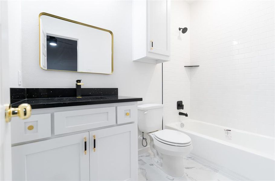 Bathroom featuring marble finish floor, toilet, shower / tub combination, vanity, and baseboards Bathroom featuring marble finish floor, toilet, shower / tub combination, vanity, and baseboards