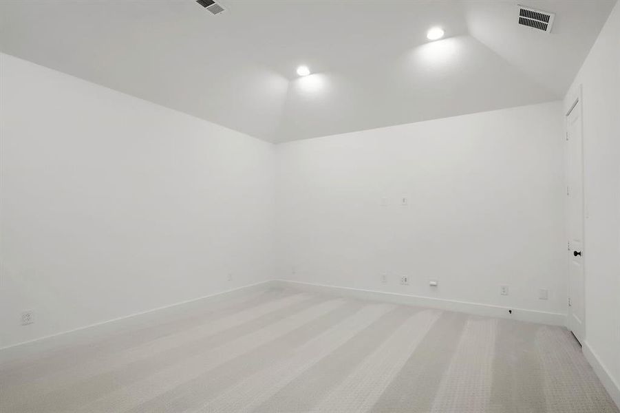 Carpeted room featuring a white interior, vaulted ceiling, recessed lighting, white baseboards, and a white door with a black knob