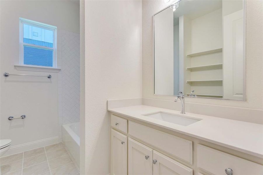 Bathroom with toilet, vanity, and tile patterned floors