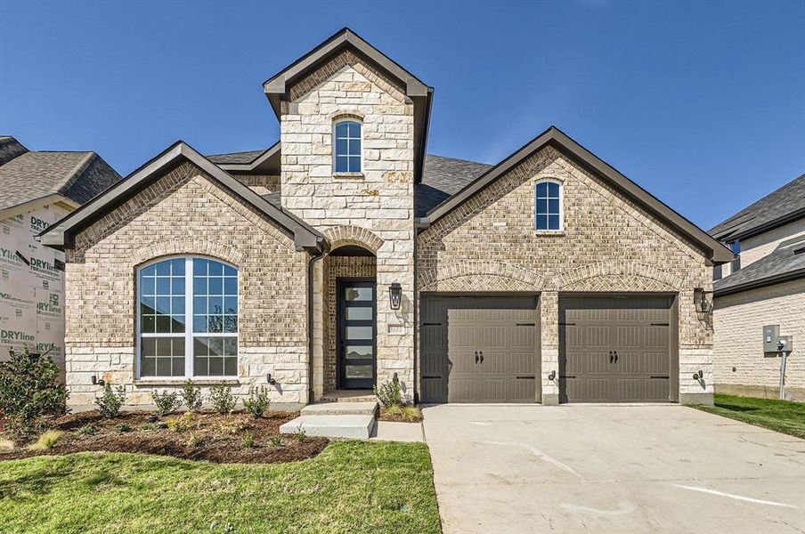 French provincial home with a front yard and a garage