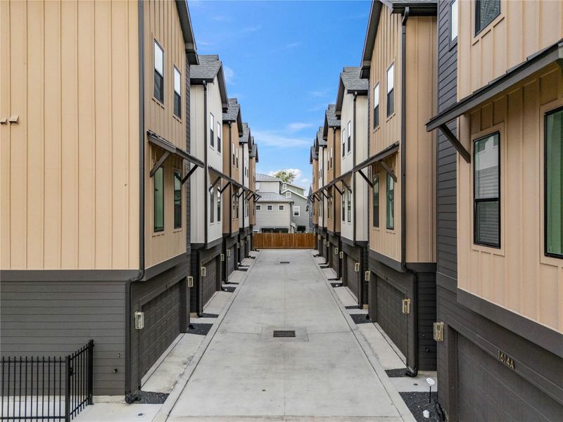 A paved driveway runs between the buildings, leading to individual garages, offering secure and convenient access.