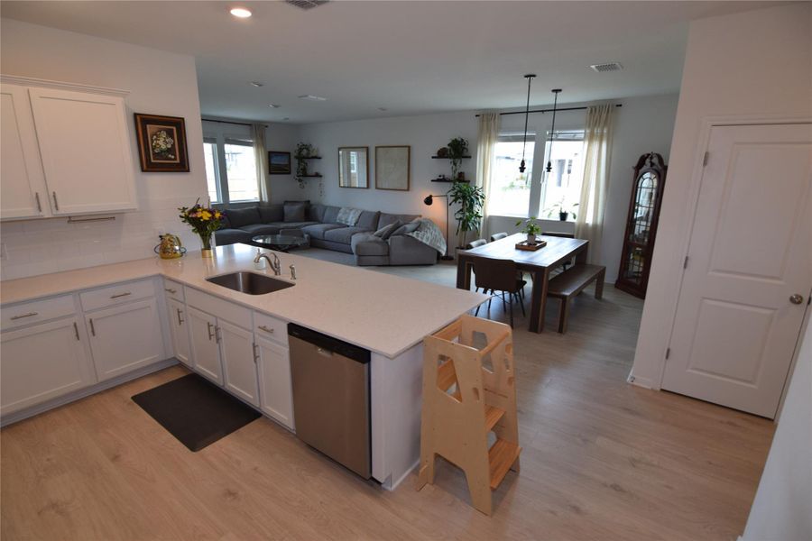 Gleaming light wood flooring unites this airy open layout connecting the kitchen and dining areas.