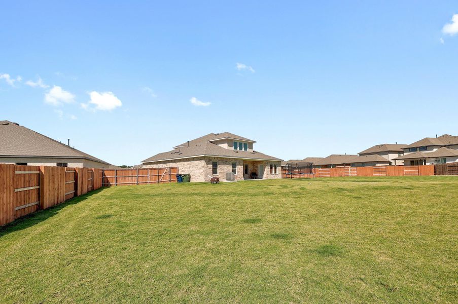 Expansive grassy yard area featuring a full privacy fence Expansive grassy yard area featuring a full privacy fence