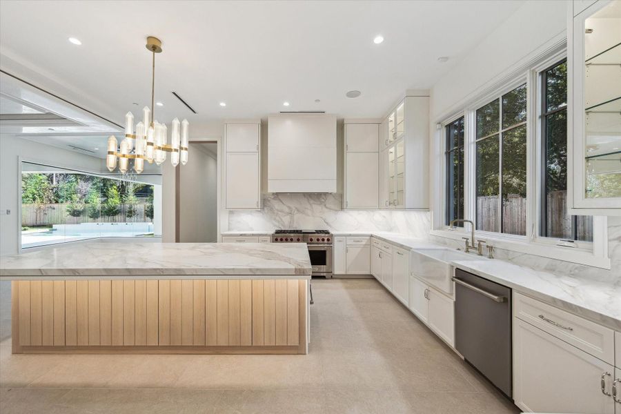 This chef-worthy kitchen features a Wolf 6-burner gas range with griddle, custom vent hood, double ovens, a 32" ceramic apron-front sink, and full-height custom cabinetry, where refined design meets professional-grade functionality.