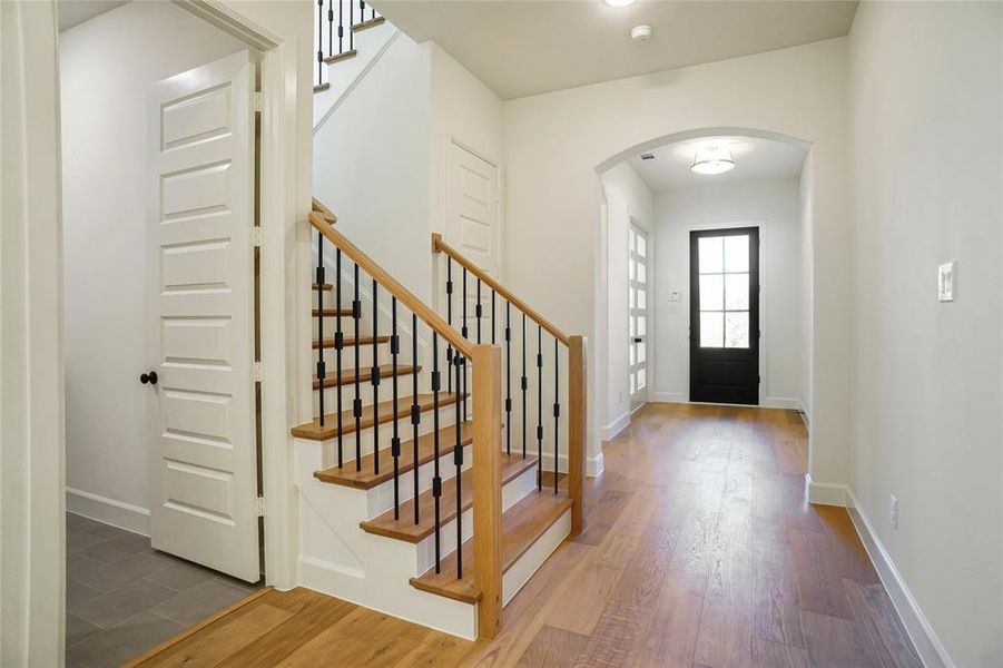 Entryway with arched walkways, wood finished floors, and stairs