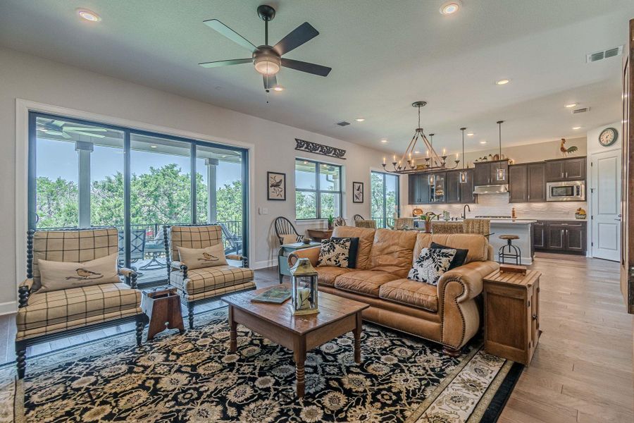 Living room featuring a ceiling fan, light wood-style flooring, a chandelier, and recessed lighting
