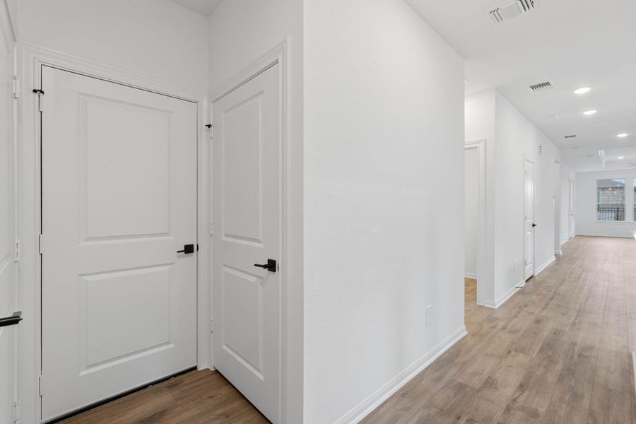 Bright, airy hallway featuring recessed lighting and warm flooring, highlighting the home’s open and inviting atmosphere.