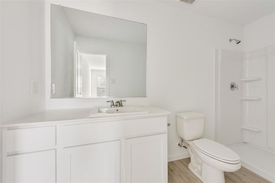 Bathroom with wood-type flooring, toilet, walk in shower, and vanity