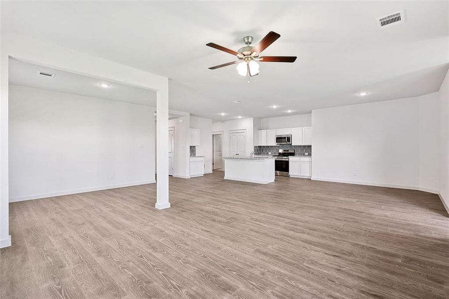 Unfurnished living room featuring ceiling fan, light wood-type flooring, and sink